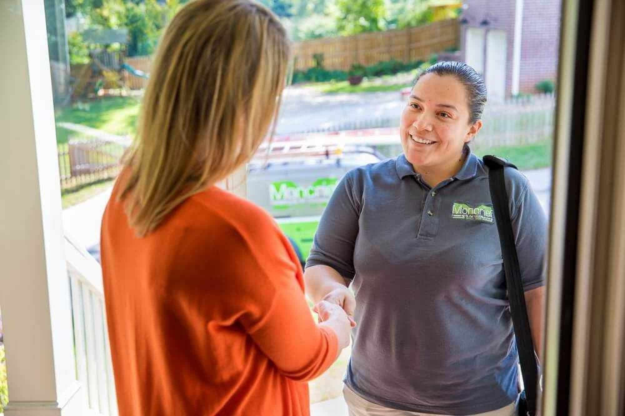 Moncrief Heating and Air Conditioning at customer's door shaking hands for heating maintenance appointment