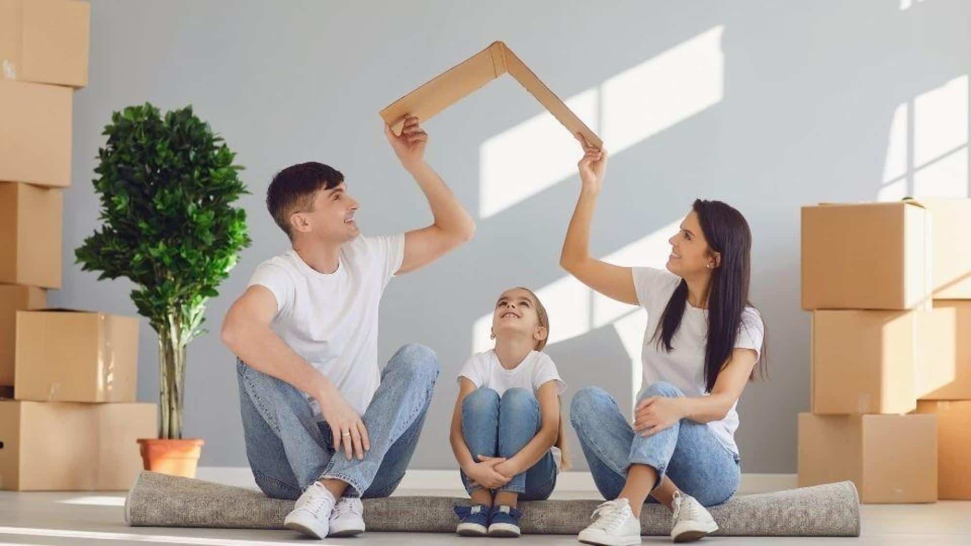 Parents sitting with their toddler in living room filled with cardboard boxes