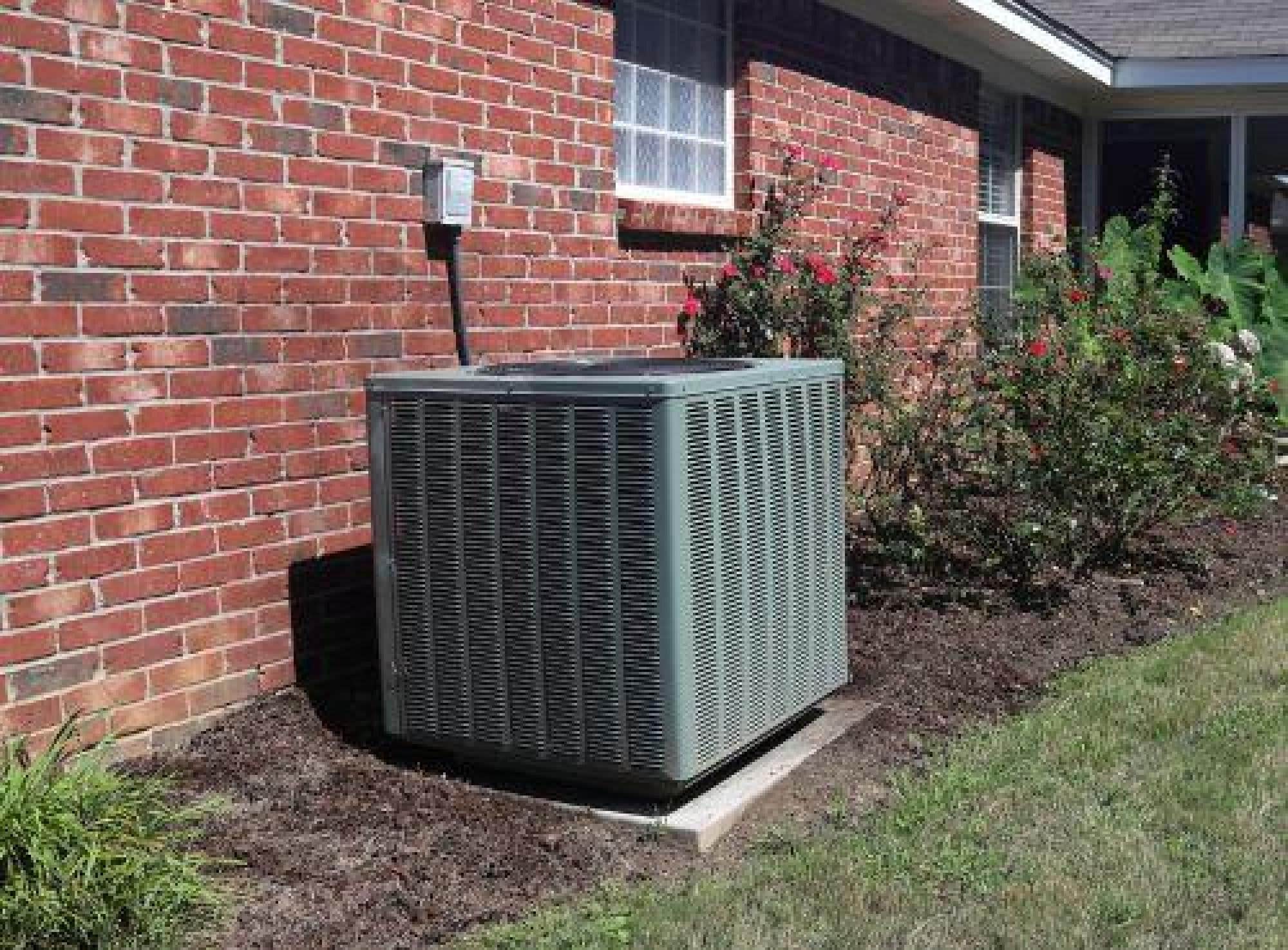 HVAC Unit Installed Outside A Home Next To Shrubs
