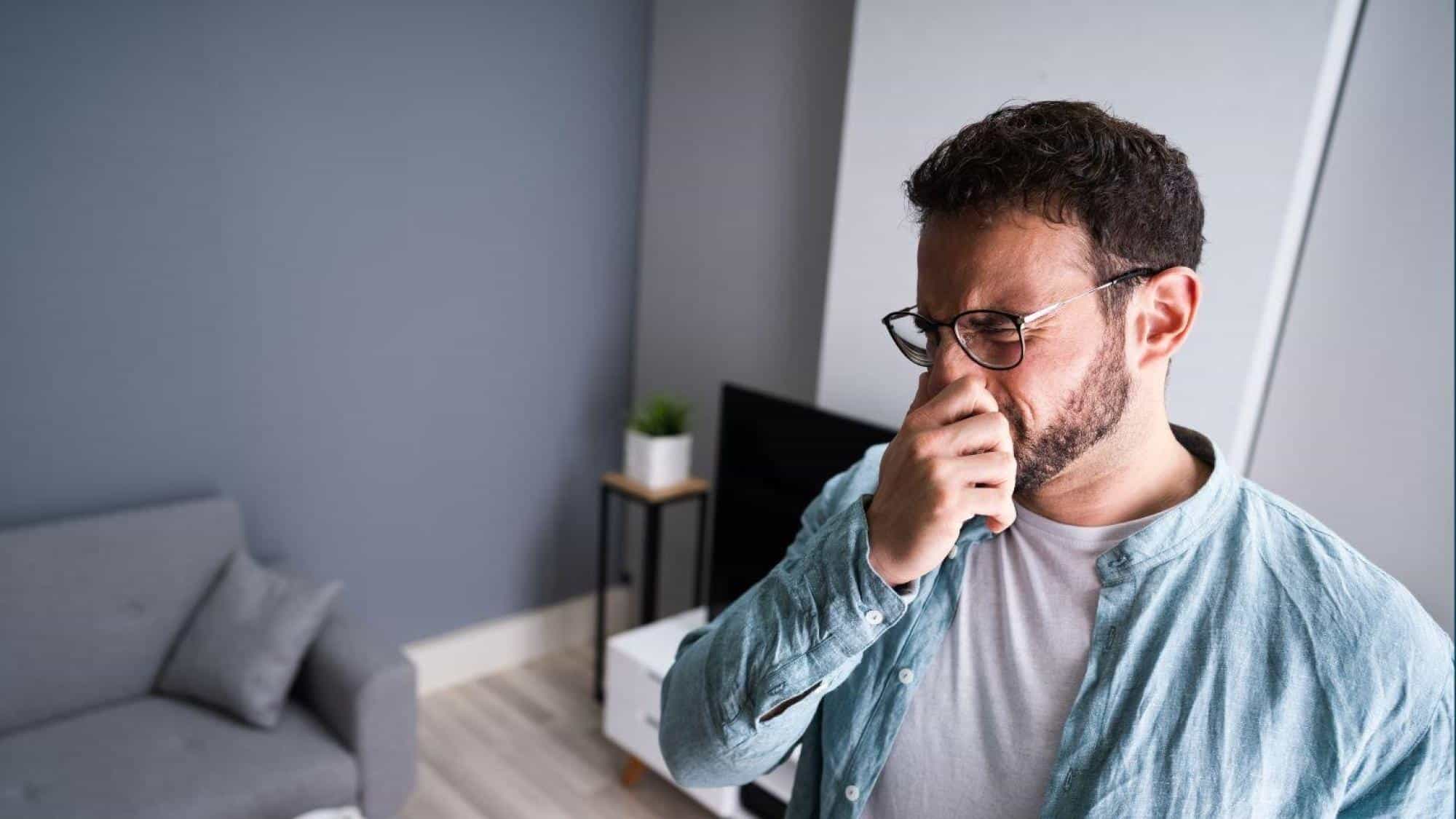 Man Covering Nose Due To Burning Smell